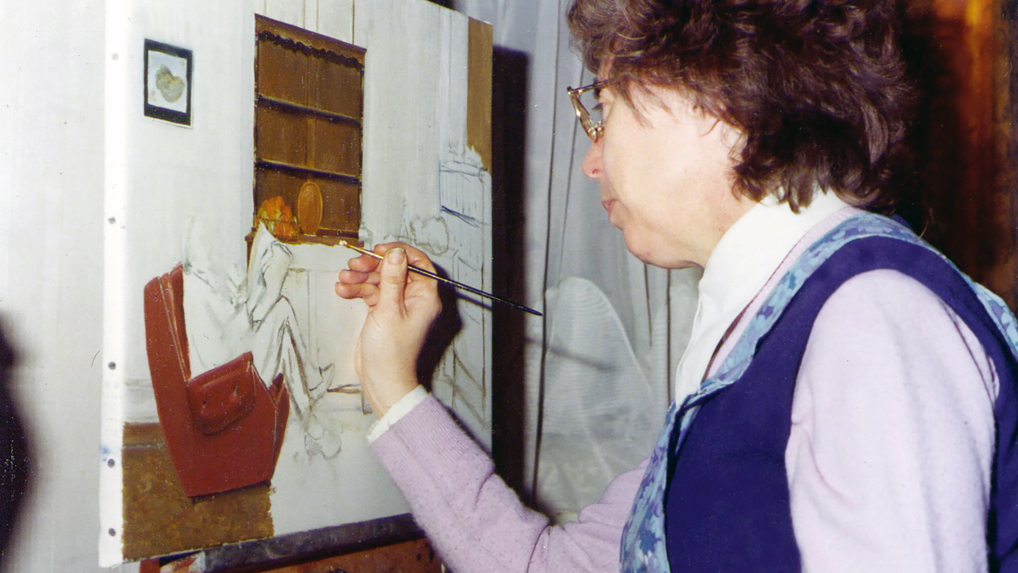 Mary painting in her living room.